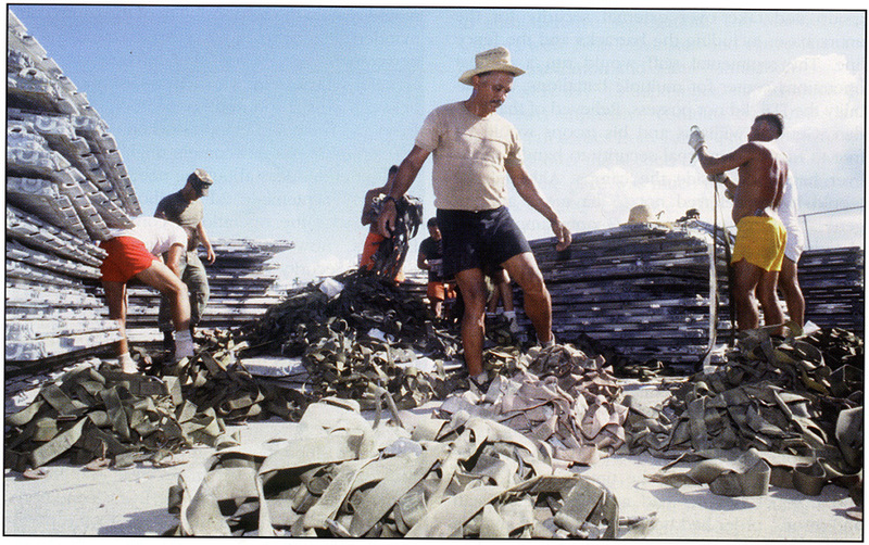 Cpl Manuel Terg and a group of Cuban migrants sort out cargo tie down straps awaiting shipment