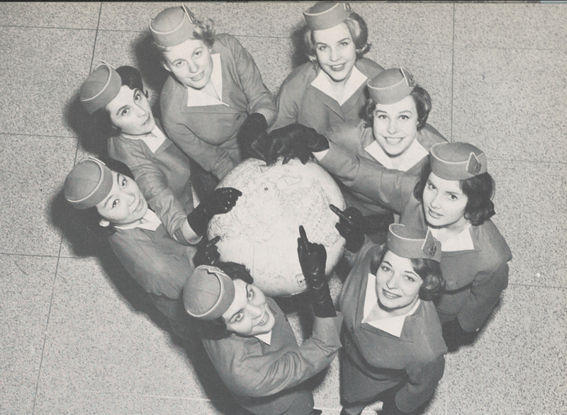 Photograph of stewardesses from Pan Am's Overseas Division surrounding a globe pointing to their respective homelands