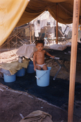 Cuban child standing in a bucket at Guantanamo Bay Naval Base, 1990s