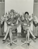 Two Pan Am stewardesses hold flags from countries serviced by Pan American World Airways